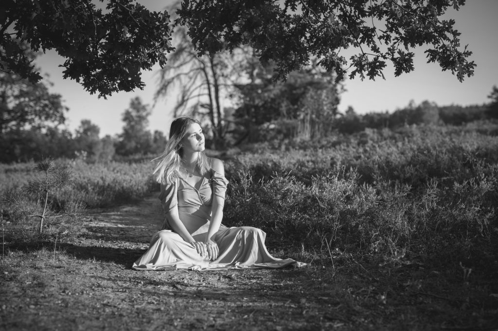 schwarz-weiß Foto einer sitzenden Frau in der Heide